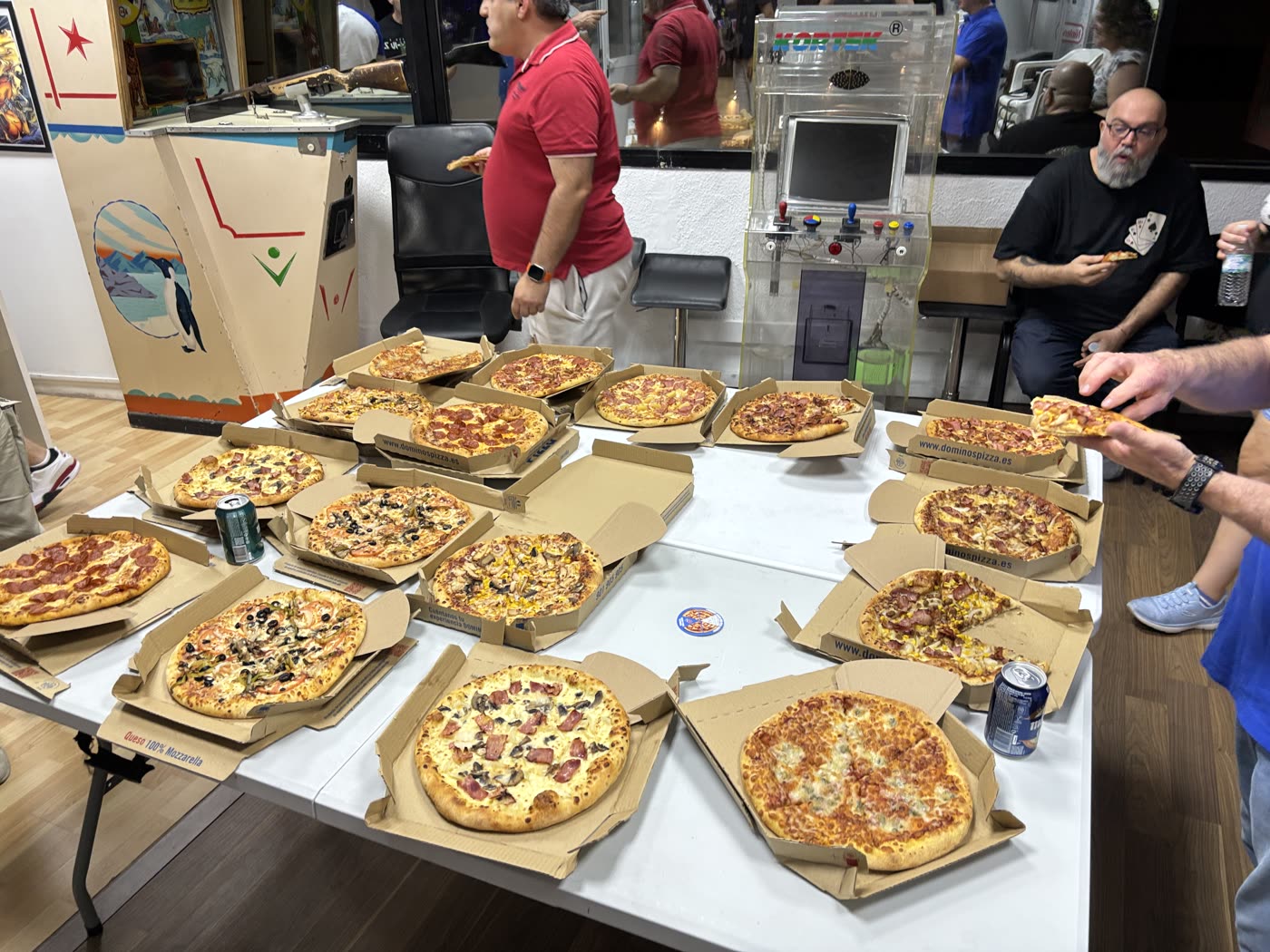 Mesa llena de cajas de pizza abiertas durante la cena con los asistentes a la presentación