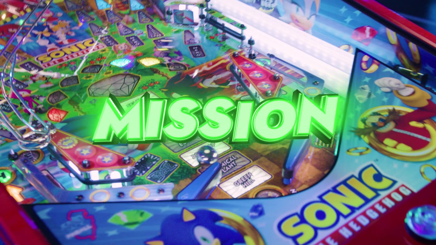 Fotograma del playfield superior de Sonic the Hedgehog con el rótulo animado "MISSION" iluminado en verde sobre las Chaos Emeralds