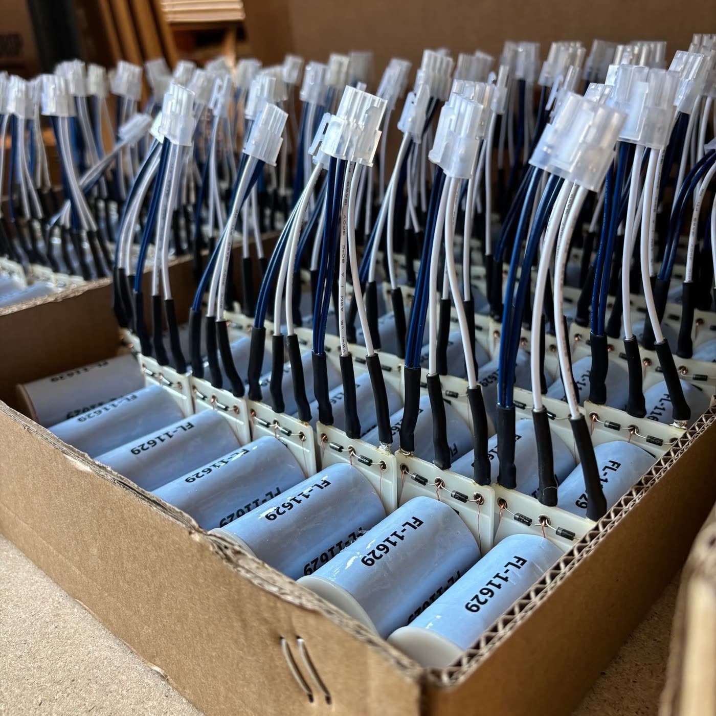 Caja llena de bobinas y componentes electrónicos con cables listos para el montaje