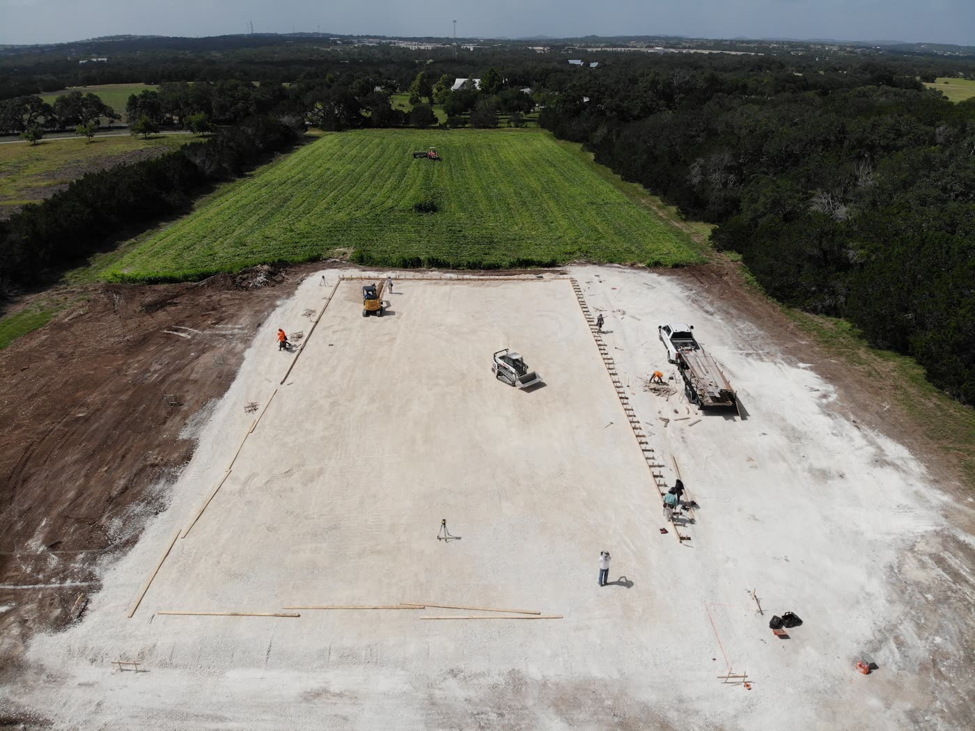 Vista aérea del solar ya nivelado, con maquinaria y equipo trabajando sobre el terreno preparado para la losa